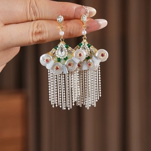 Macro detail of vintage fan-shaped earrings with rhinestones, pearls and beaded tassels