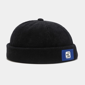 Detail showing corduroy texture and fashion label on the side of a black docker hat