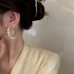 Elegant gold geometric hoop earrings with cubic zirconia crystals worn by a model