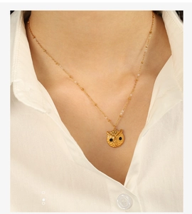 Detailed close-up of a golden owl pendant necklace with black diamond eyes on a model
