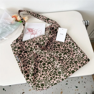 Close-up of floral canvas tote bag with pink and green patterns on white table