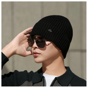 Close-up of black ribbed knit beanie with mountain logo badge and thick warm texture