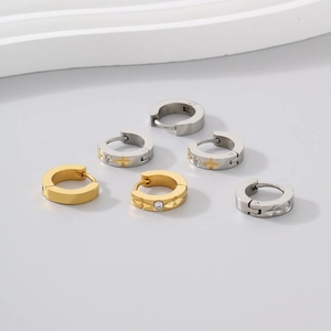 Macro detail of C-shaped steel earrings with star texture and zircon stones