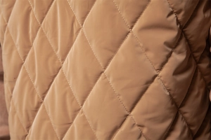 Macro shot of khaki quilted fabric with high-quality diamond stitching and matte texture