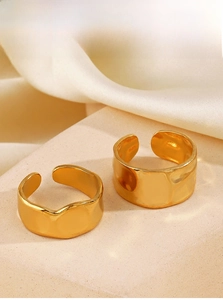 Detail of two adjustable gold-plated lava texture rings on an elegant stone surface