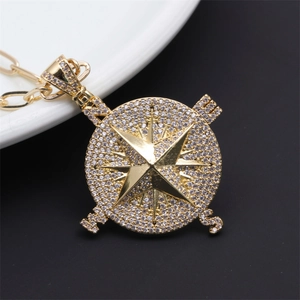 Macro detail of golden compass pendant necklace featuring micro-set zircon and NESW letters