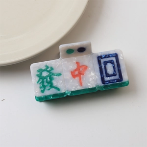 Macro shot of Mahjong themed hair claw clip with Chinese characters Fa and Zhong