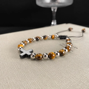 Dettaglio di bracciale con pietre occhio di tigre e ciondolo a croce nera su corda