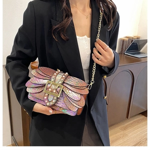 Detail of colorful snake-texture leather handbag featuring a gold buckle and chain strap