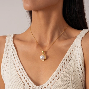 Close-up of elegant pearl pendant with gold plating and cubic zirconia on a female model