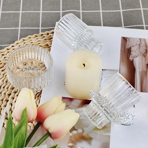 Détail de bougeoirs en verre strié sur un tapis texturé avec des touches florales