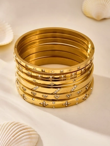 Macro detail of stacked 18K gold-plated stainless steel bangles with zircon accents