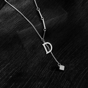 Detail of silver letter D pendant and metal bar accents on minimalist necklace