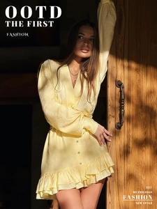Detail of light yellow V-neck dress with buttons and textured flowy fabric in sunlight