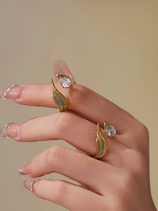 Detailed macro view of golden wing rings featuring blue matte finish and teardrop zircon