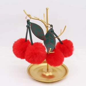 Detail of red plush cherry keychains with green leather leaves and gold metal ring
