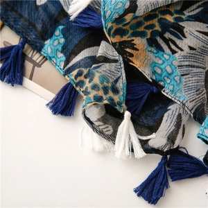 Detailed macro view of navy leaf print scarf fabric texture and tassel fringe details