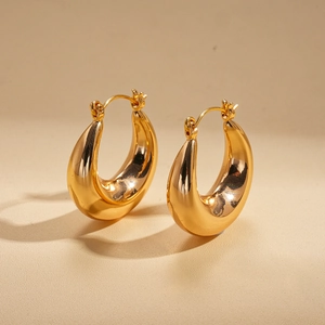 Detailed view of chunky U-shaped gold plated earrings with a high-polished metallic finish