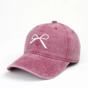 Détail d'une casquette vintage en coton délavé rose avec broderie nœud blanc élégante