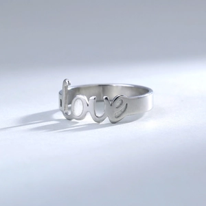Detailed side view of silver stainless steel ring featuring minimalist love lettering design