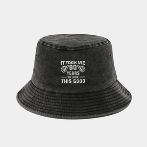 Detail of washed cotton bucket hat with white IT TOOK ME 80 YEARS TO LOOK THIS GOOD embroidery
