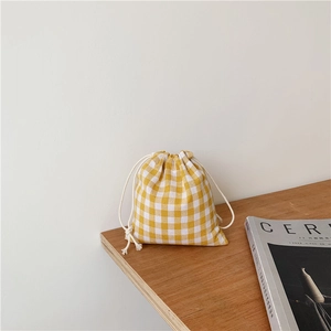 Detail of yellow plaid cotton drawstring bag on a wooden table with a magazine