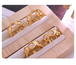 Detail of 18K gold plated titanium rings with infinity cut-outs on a wooden stand