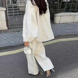 Outdoor shot of white linen set featuring puffy lantern sleeves with embroidery detail