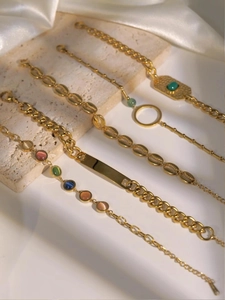 Dettaglio di bracciali cubani in acciaio dorato con gemme colorate e inserti in madreperla