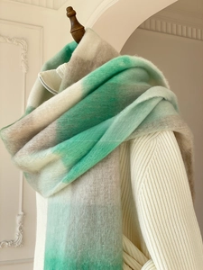 Close-up of the soft fuzzy texture and gradient green knit on a thick winter shawl