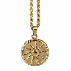 Détail macro du pendentif soleil en acier doré sur une chaîne torsadée pour homme