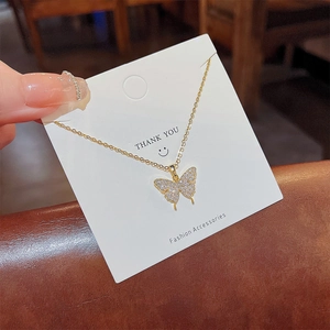 Détail du collier papillon doré serti de zircons brillants sur carte de cadeau