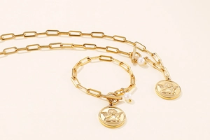 Detail of gold angel coin necklace and bracelet set with paperclip chain and pearl