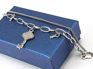 Macro view of silver layered heart and key charm bracelet on a textured gift box