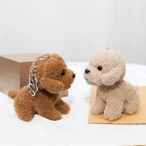 Close-up of brown and beige curly plush teddy dog pendants with silver metal keychains