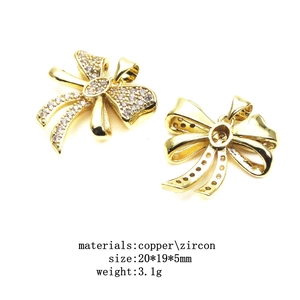 Macro detail of gold bow pendant with zircon inlays and precise measurements
