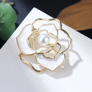 Detailed close-up of a white camellia flower brooch with gold hollow petals and a pearl center