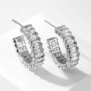 Vue macro de boucles d'oreilles argentées en C avec zircons cubiques taillés en baguette
