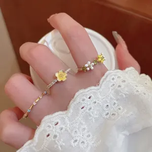 Floral gold rings with yellow petals, small pearls and sparkling crystals on model hand