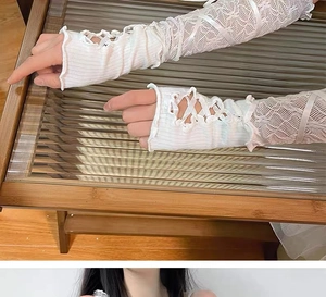 Detail of white lace sleeve with ribbon criss-cross straps and ruffled edges in Y2K style