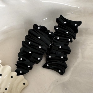 Macro detail of wrinkled texture hair clips with black and cream polka dot patterns