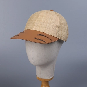 Straw baseball cap with brown leather brim and decorative cutout details on a mannequin