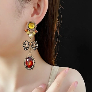 Vintage palace style earrings with yellow stones, black bow, and orange oval pendants
