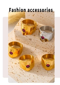 Detail of adjustable stainless steel rings with red zircon stones on beige stone display