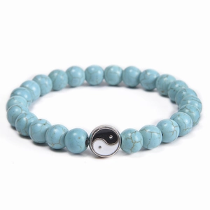 Detailed view of blue turquoise beads with Yin Yang charm on an elastic cord bracelet