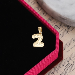 Macro shot of gold number 2 pendant with honeycomb texture in a jewelry gift box