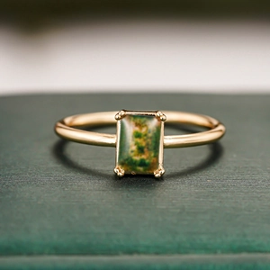 Macro shot of rectangular moss agate gemstone in a four-prong gold plated ring setting