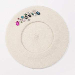 Detailed texture of beige wool beret featuring multi-colored rhinestones and gems