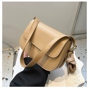 Detailed macro view of beige leather flap crossbody bag with fine stitching and wide strap