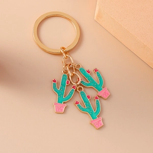 Detail view of golden metal keychain featuring three green enamel cactus charms in pink pots